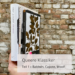 Eine Hand hält die Bücher »Orlando« (Virginia Woolf), »Breakfast at Tiffany's« (Truman Capote) und »Giovannie's Room« (James Baldwin) vor einer Steinwand. Davor steht die Überschrift des Artikels: Queere Klassiker. Teil 1 – Baldwin, Capote, Woolf.